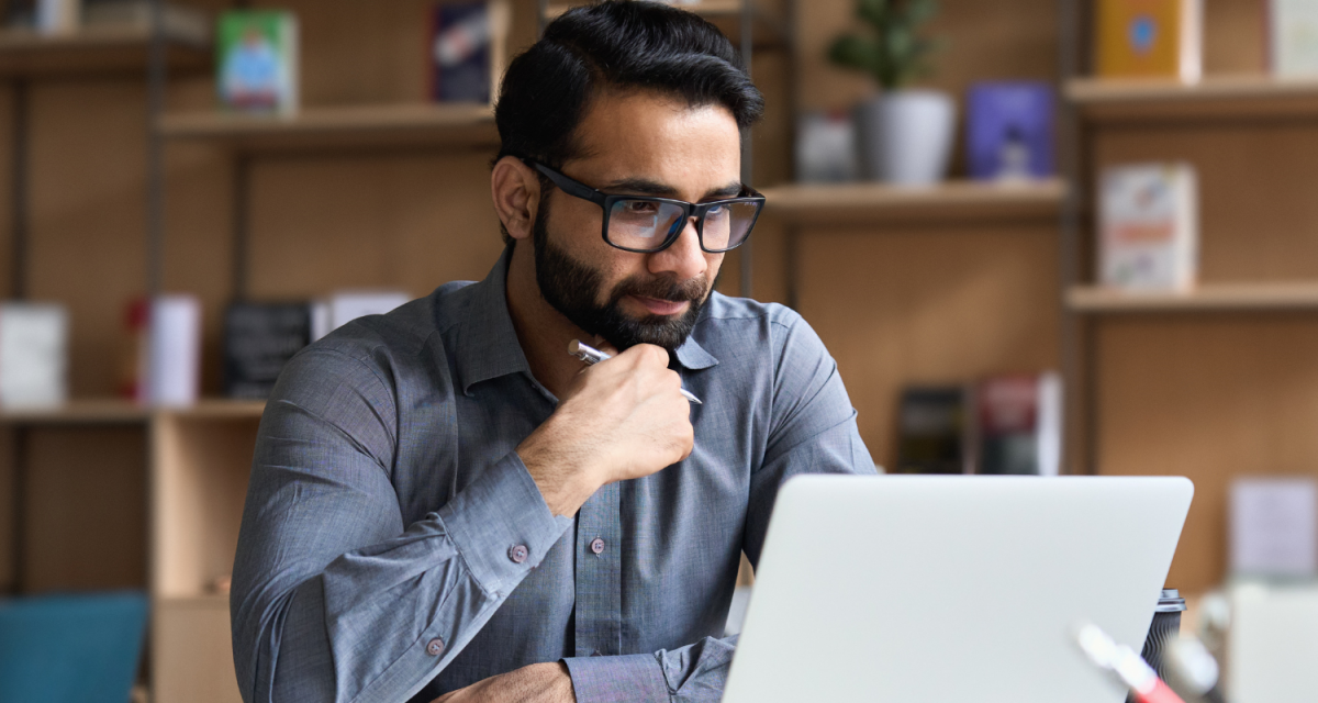 Man sitting in front of a laptop with his hand raised to his chin